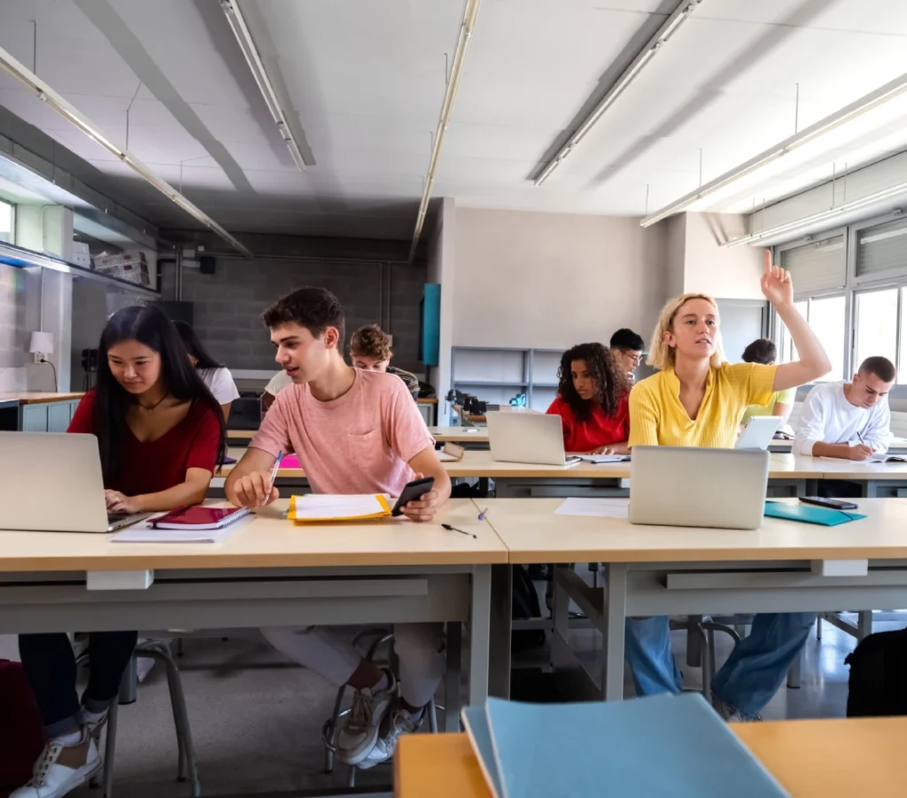 Students studying in a classroom with laptops.