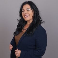 Smiling woman in blue blazer posing confidently.