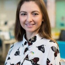 Woman smiling in butterfly-patterned shirt.