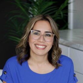 Brown-haired woman with glasses wearing a blue shirt.